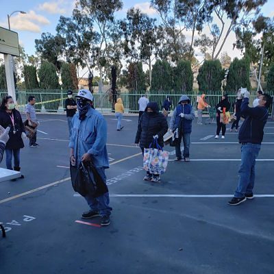 Those waiting in line to receive food are required to wear masks and gloves and stand six feet apart.